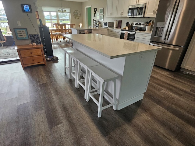 kitchen with white cabinetry, kitchen peninsula, a breakfast bar area, appliances with stainless steel finishes, and pendant lighting