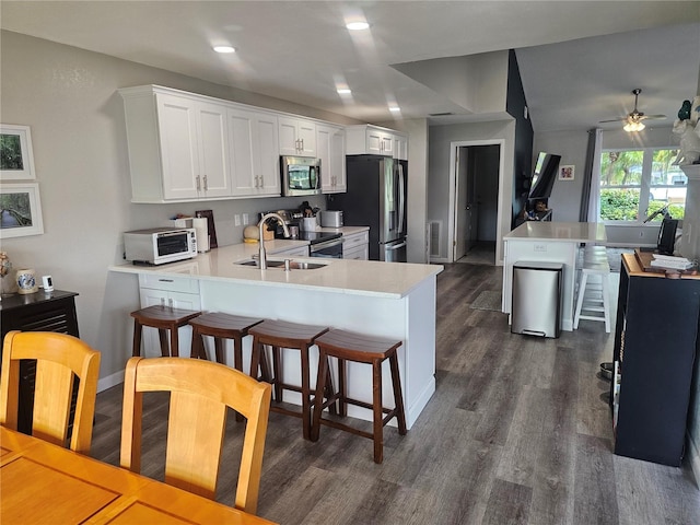 kitchen with white cabinetry, appliances with stainless steel finishes, kitchen peninsula, and a breakfast bar area