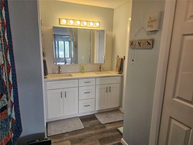 bathroom featuring a textured ceiling, decorative backsplash, wood-type flooring, and vanity