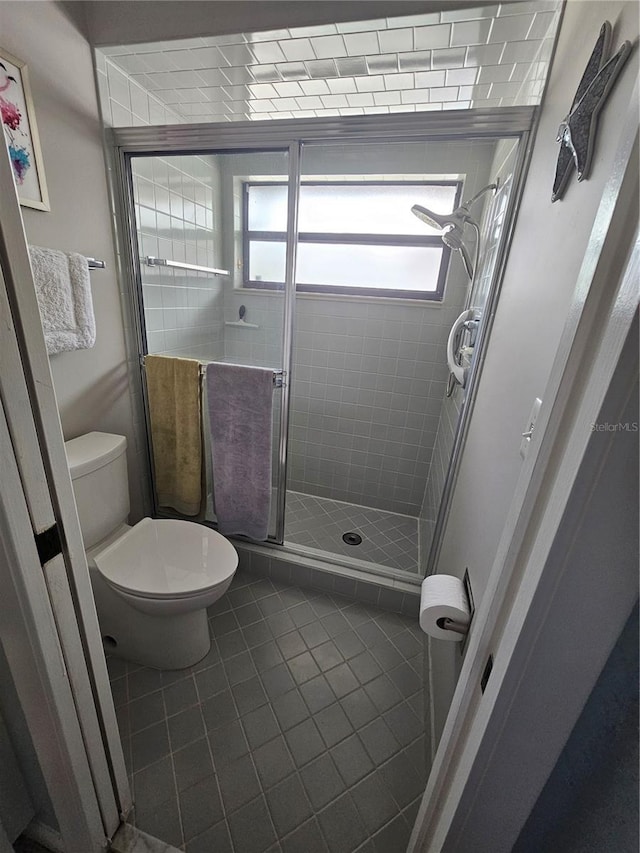 bathroom featuring walk in shower, tile patterned floors, and toilet