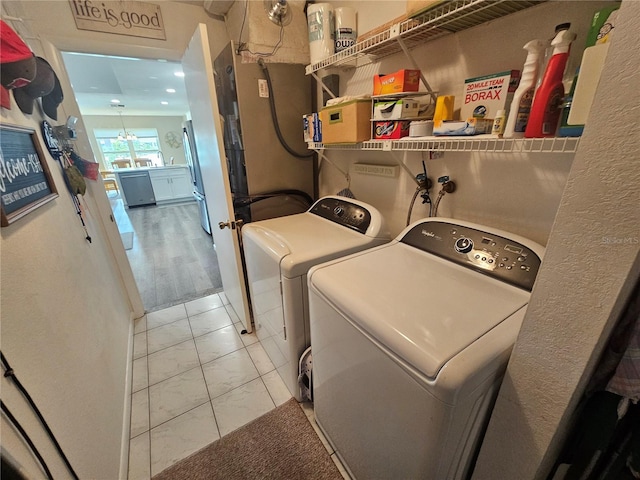 laundry room featuring light tile patterned floors, a chandelier, and washer and clothes dryer