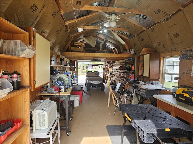 miscellaneous room with ceiling fan, wooden walls, and a workshop area