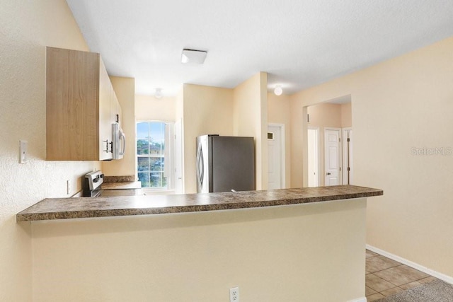 kitchen featuring kitchen peninsula, light tile patterned flooring, and stainless steel appliances