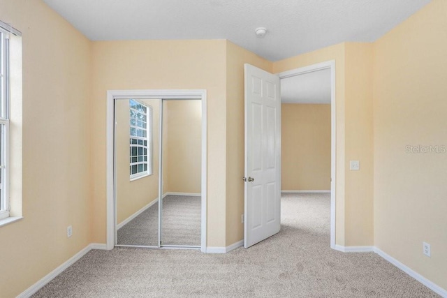 unfurnished bedroom featuring light carpet and a closet