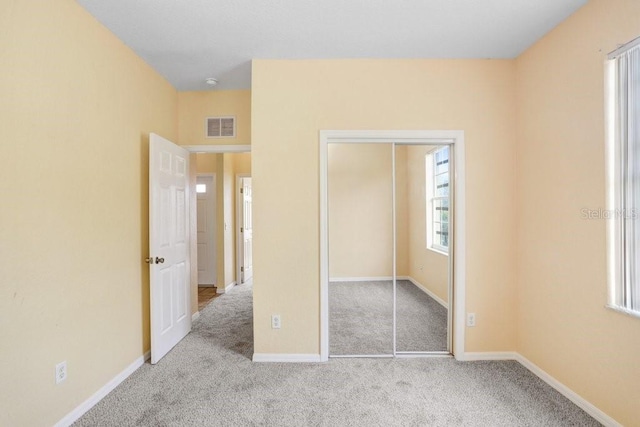 unfurnished bedroom with light colored carpet and a closet