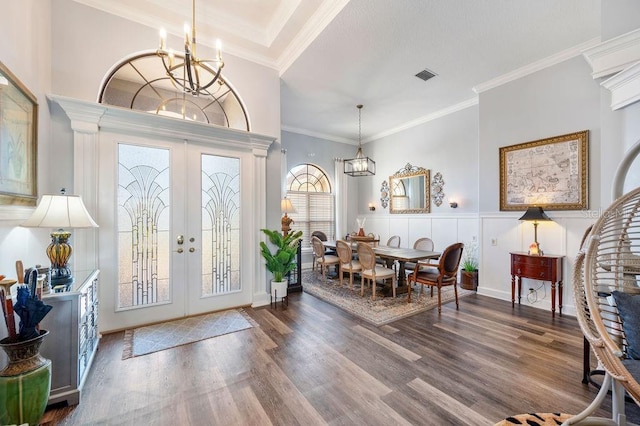 foyer with crown molding, hardwood / wood-style floors, a notable chandelier, and french doors