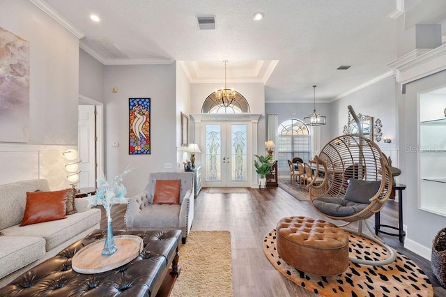 foyer entrance with wood-type flooring, crown molding, a chandelier, and french doors