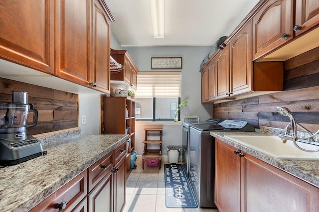 laundry area with washer and dryer, wood walls, sink, cabinets, and light tile patterned floors