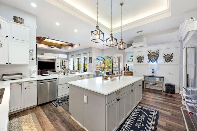 kitchen with dishwasher, white cabinetry, sink, hanging light fixtures, and a tray ceiling