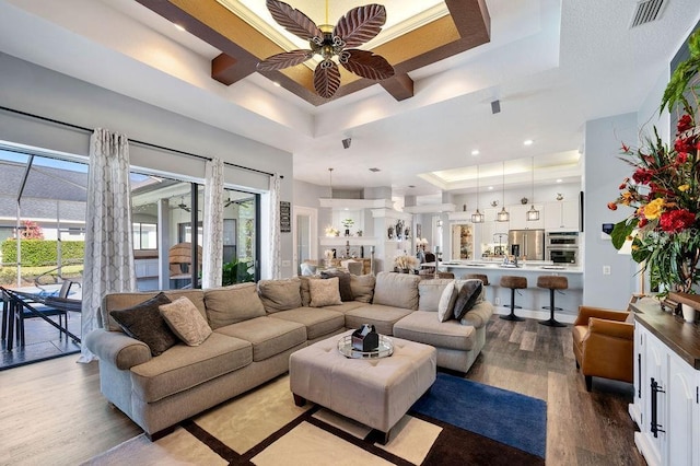 living room with light hardwood / wood-style flooring, ceiling fan, and a tray ceiling