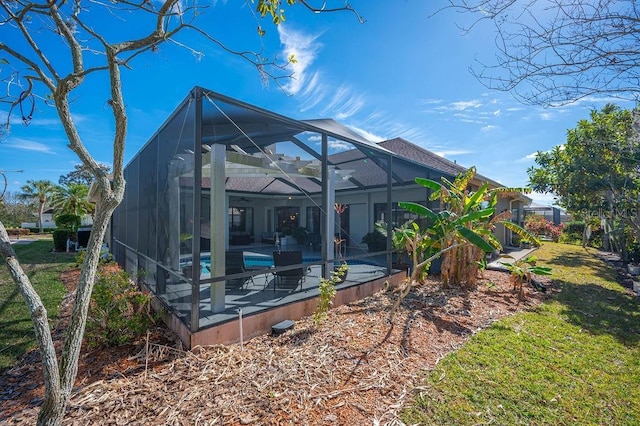 back of property featuring a yard, a patio area, and glass enclosure