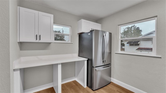 kitchen with white cabinets, light hardwood / wood-style flooring, and stainless steel refrigerator