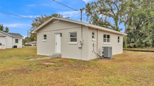 back of property featuring central AC unit and a yard