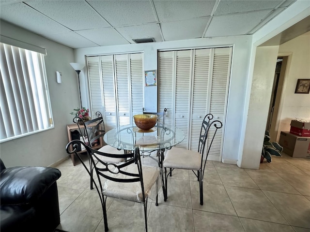 tiled dining space with a drop ceiling