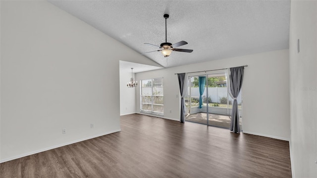 empty room with vaulted ceiling, dark hardwood / wood-style flooring, ceiling fan with notable chandelier, and a textured ceiling