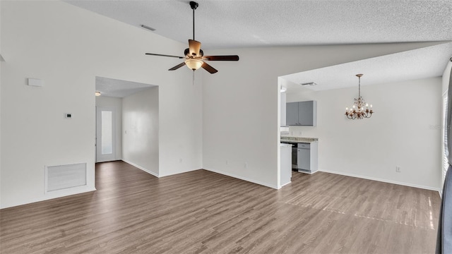 unfurnished living room featuring ceiling fan with notable chandelier, hardwood / wood-style flooring, a textured ceiling, and lofted ceiling