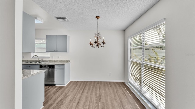 kitchen with pendant lighting, dishwasher, sink, gray cabinetry, and light stone counters