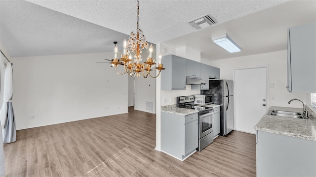 kitchen featuring sink, a textured ceiling, appliances with stainless steel finishes, and vaulted ceiling