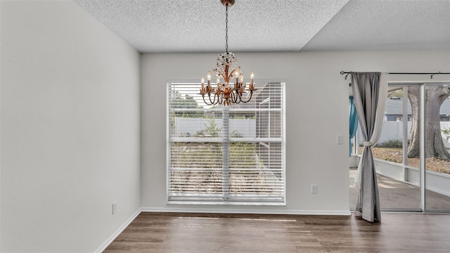 unfurnished dining area featuring a textured ceiling, dark hardwood / wood-style flooring, and an inviting chandelier