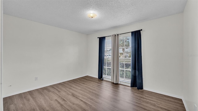 spare room featuring wood-type flooring and a textured ceiling