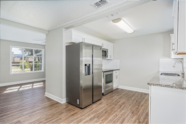 kitchen featuring sink, tasteful backsplash, light hardwood / wood-style flooring, appliances with stainless steel finishes, and white cabinets