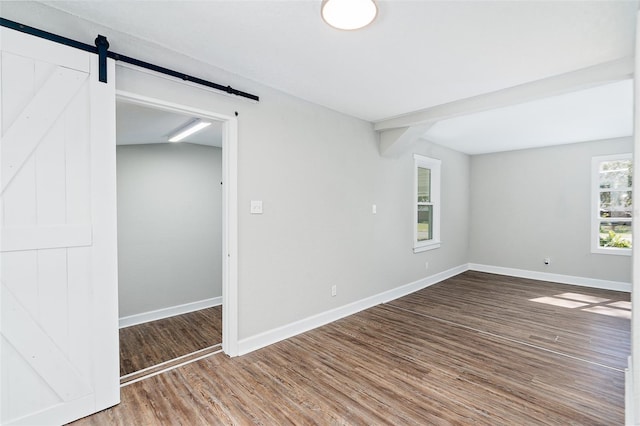 unfurnished room featuring a barn door and hardwood / wood-style floors