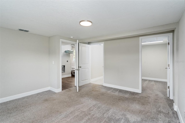 unfurnished bedroom featuring a spacious closet, a closet, a textured ceiling, and carpet flooring