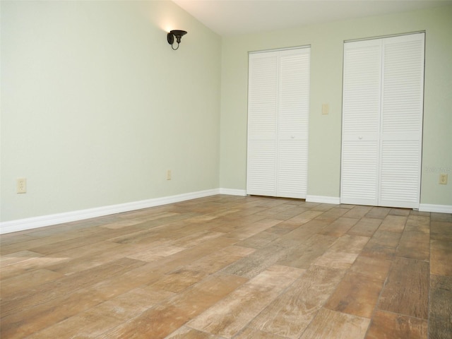 unfurnished bedroom featuring multiple closets and light wood-type flooring