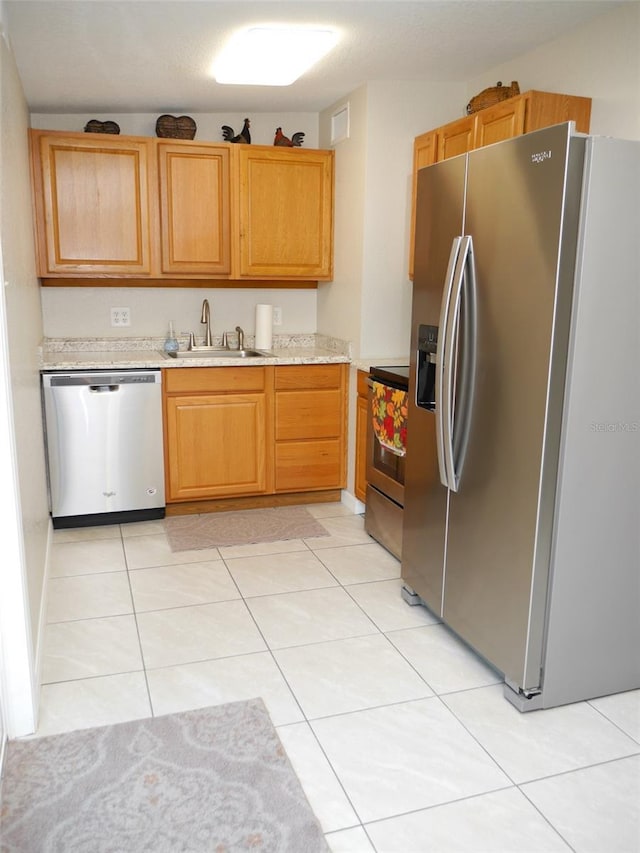 kitchen featuring appliances with stainless steel finishes, sink, and light tile patterned floors