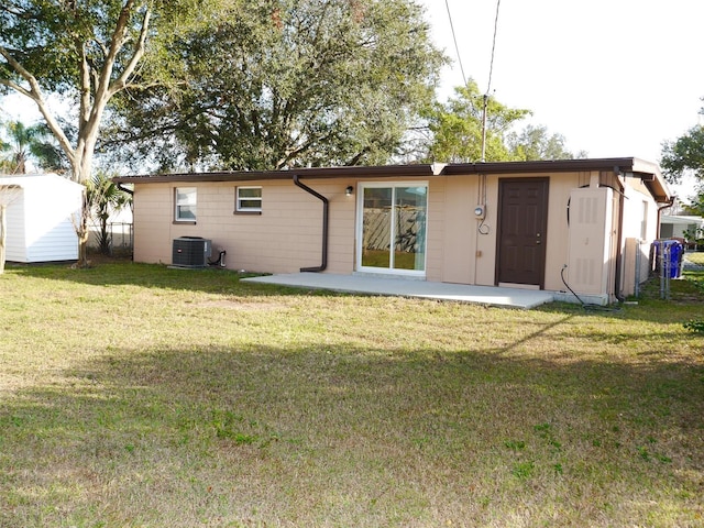 back of property featuring cooling unit, a storage unit, a patio area, and a lawn