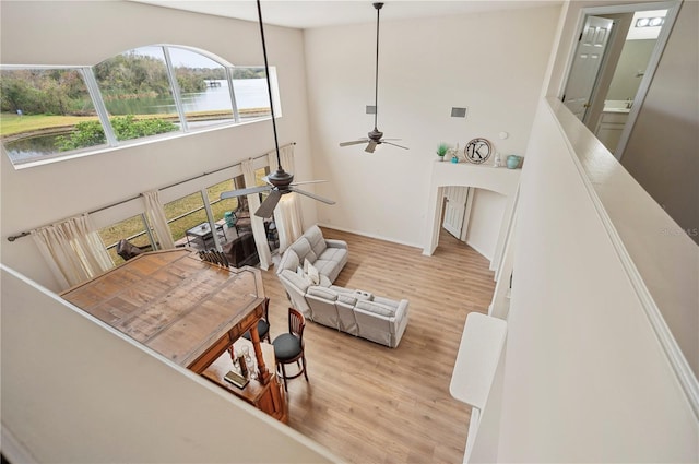 living room featuring a towering ceiling, light hardwood / wood-style floors, and ceiling fan