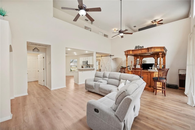 living room featuring a high ceiling, ceiling fan, and light hardwood / wood-style flooring