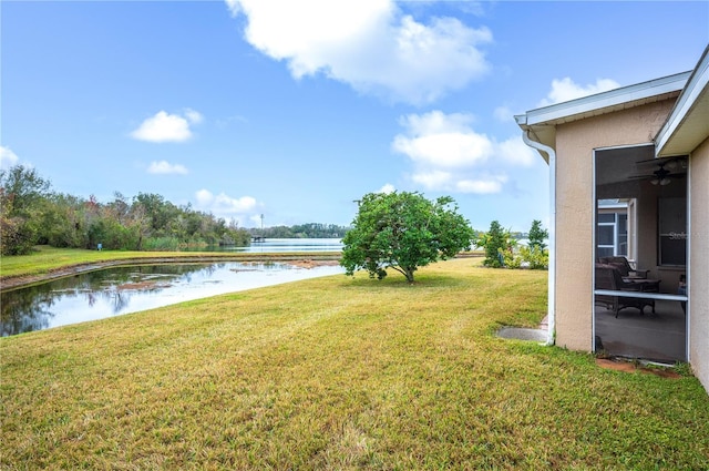 view of yard with ceiling fan and a water view