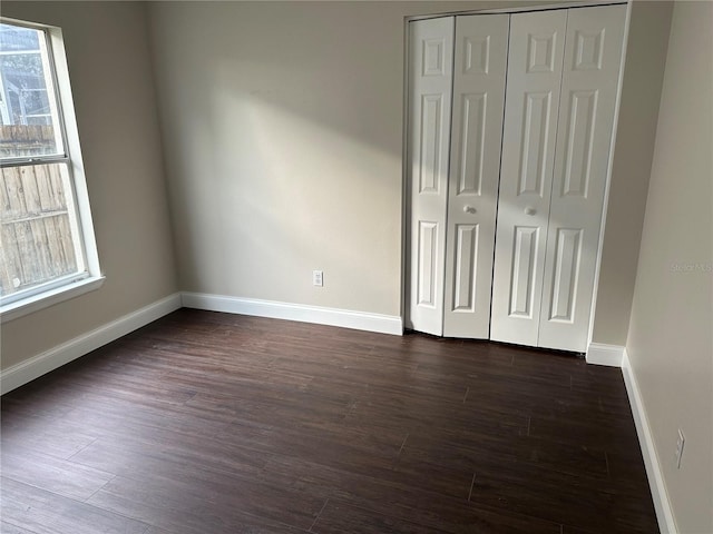 unfurnished bedroom with a closet and dark hardwood / wood-style floors