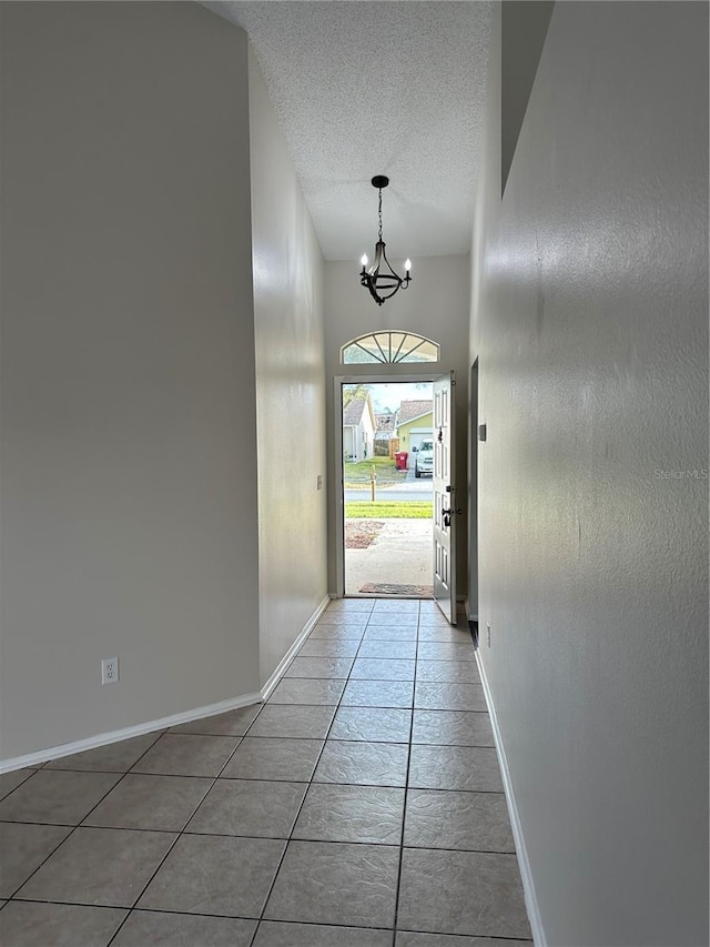 doorway to outside featuring a textured ceiling, tile patterned flooring, and an inviting chandelier