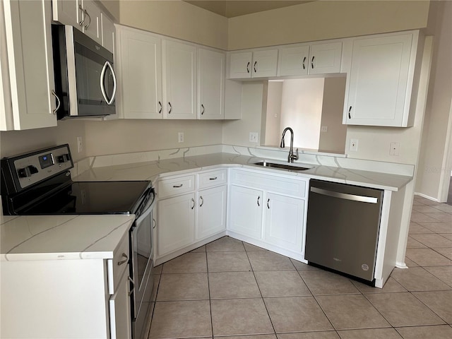 kitchen with white cabinetry, stainless steel appliances, light stone countertops, sink, and light tile patterned floors