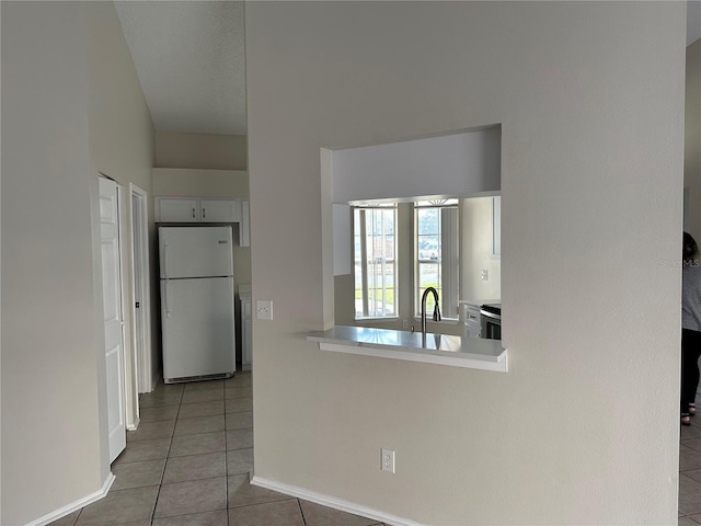 kitchen with stainless steel electric range oven, white refrigerator, tile patterned floors, sink, and white cabinetry