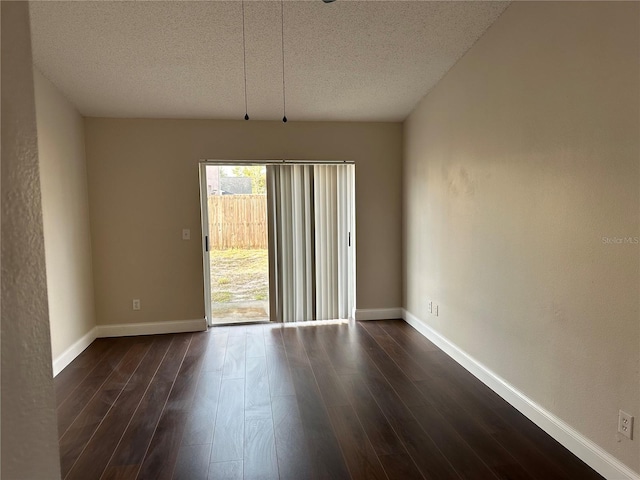 spare room featuring a textured ceiling and dark hardwood / wood-style floors