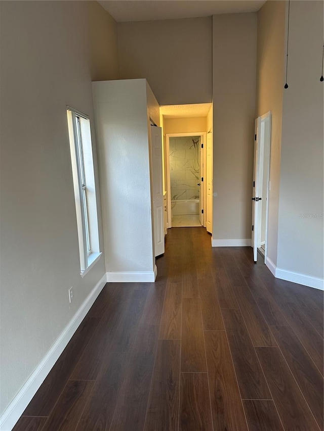 unfurnished room with dark wood-type flooring and a towering ceiling