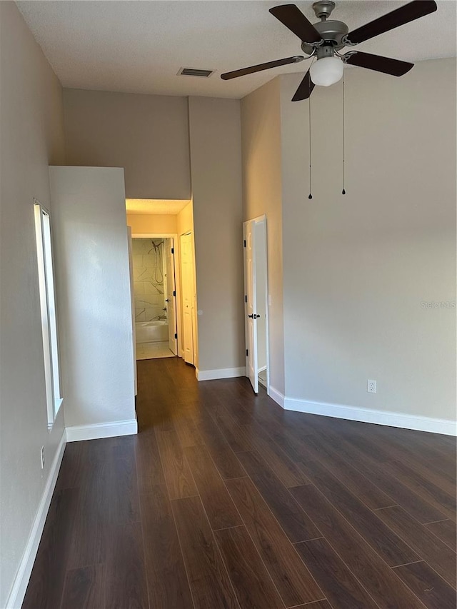 empty room with dark hardwood / wood-style flooring, ceiling fan, and a towering ceiling