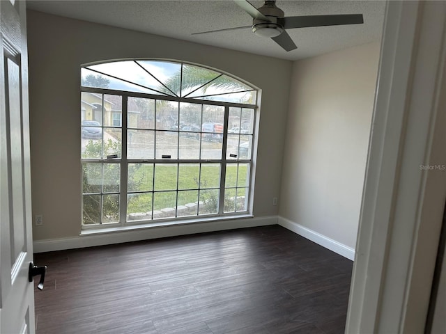 spare room with a textured ceiling, ceiling fan, and dark hardwood / wood-style flooring