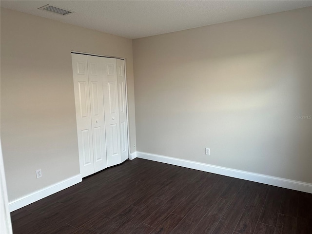 unfurnished bedroom with a closet and dark hardwood / wood-style floors