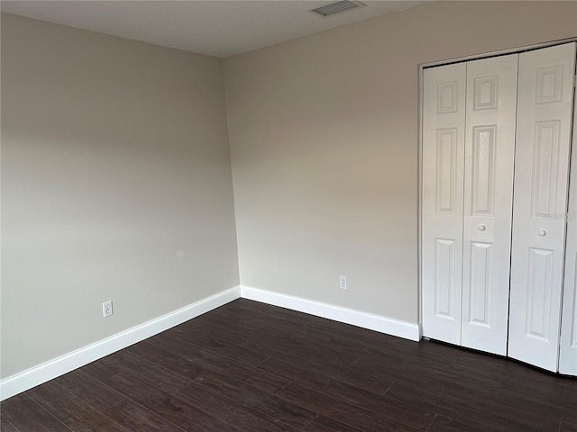 unfurnished bedroom with a closet and dark hardwood / wood-style floors