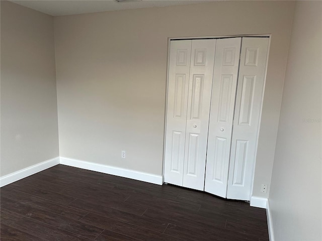 unfurnished bedroom featuring a closet and dark hardwood / wood-style floors