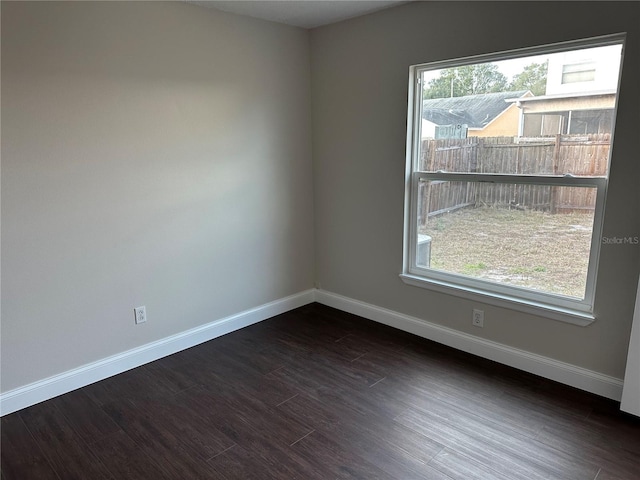 empty room with dark hardwood / wood-style flooring and plenty of natural light