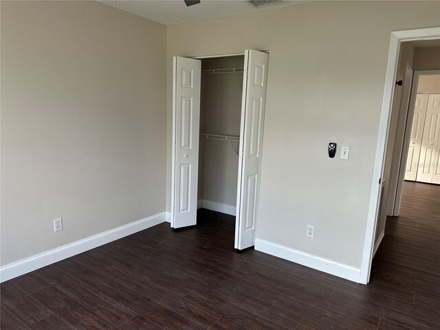 unfurnished bedroom with a closet and dark wood-type flooring