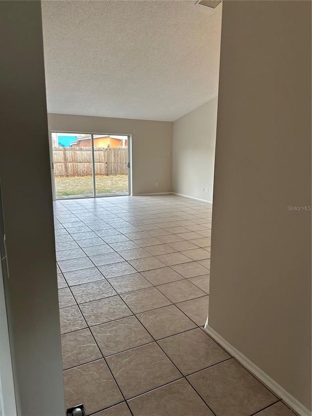 empty room featuring a textured ceiling and light tile patterned flooring