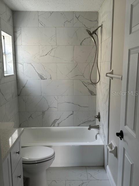 full bathroom featuring tiled shower / bath combo, toilet, a textured ceiling, and vanity