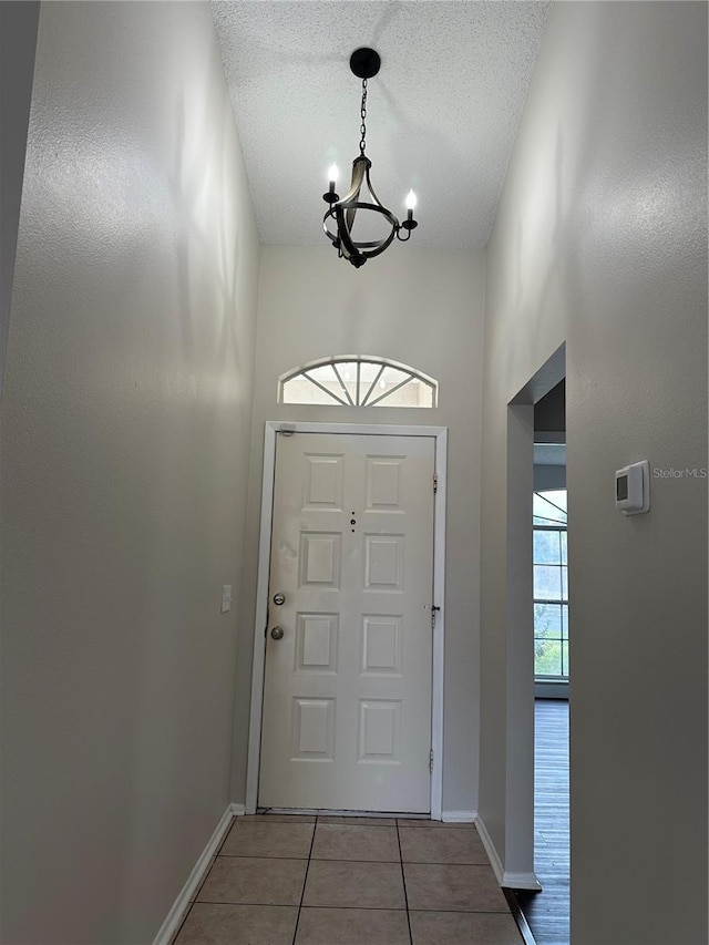 tiled foyer entrance featuring an inviting chandelier and a textured ceiling