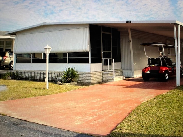 view of front of property with a carport, a sunroom, and a front lawn